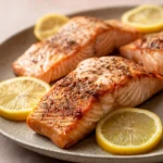 Close-up of air fryer salmon fillets with a golden crust on a clean white plate.