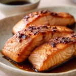 Close-up of air fryer salmon with honey soy sauce, garnished with sesame seeds and green onions.