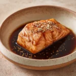 Close-up of air fryer salmon with soy sauce garnished with herbs on a white plate