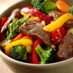 Close-up of a colorful beef stir fry dinner with vegetables on a clean plate.