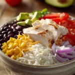 Close-up of a chicken and rice burrito bowl with fresh ingredients and vibrant colors.