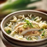 Close-up of Ginger Scallion Chicken Noodle Soup with bright, warm lighting