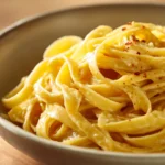 Close-up of creamy garlic pasta with cheese and herbs in a white bowl