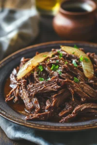 Close-up of slow cooker shredded beef with bright, warm lighting and a clean background.