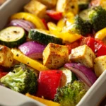 Close-up of a colorful sheet pan dinner with tofu, vegetables, and herbs