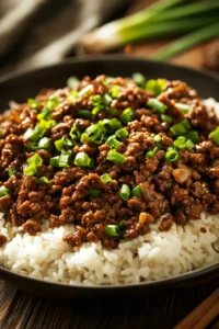 Close-up of a honey garlic beef and rice skillet with bright, warm lighting and minimal background.