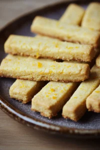 Close-up of orange shortbread cookie sticks, gluten-free, on a clean background.
