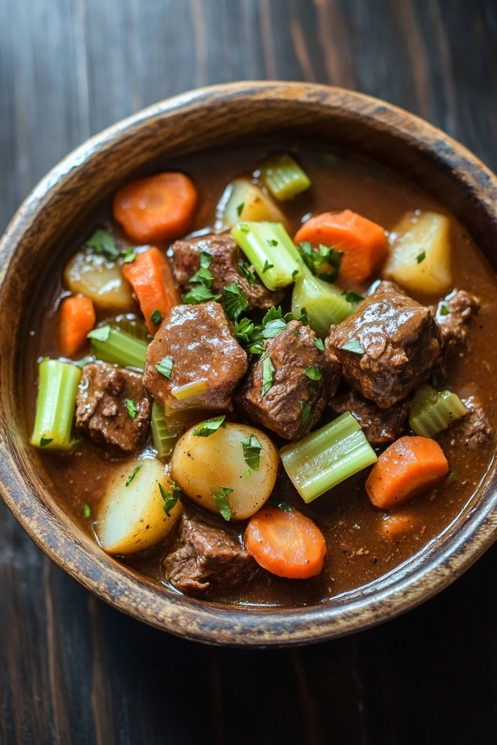 Beef stew with skillet beef stew meat - the image is a close-up of a bowl of beef stew. the stew is made with chunks of beef, carrots, celery, and potatoes. the beef is cooked in a rich, dark brown broth and is garnished with chopped parsley. the vegetables are cut into small cubes and are arranged in a circular pattern around the beef. the bowl is made of ceramic and is sitting on a wooden table. the background is blurred, making the bowl the focal point of the image.